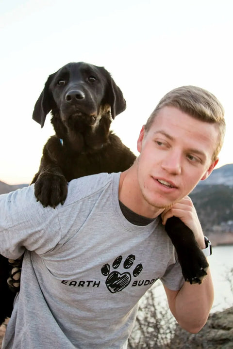 A man with a black lab puppy on his back. He is wearing an Earth Buddy t-shirt. Shop CBD apparel and CBD pet products by Earth Buddy!