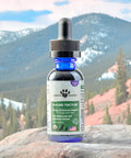Bottle of Earth Buddy Immune Tincture with a mountainous landscape in the background